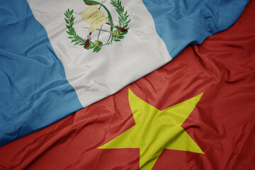 waving colorful flag of vietnam and national flag of guatemala.