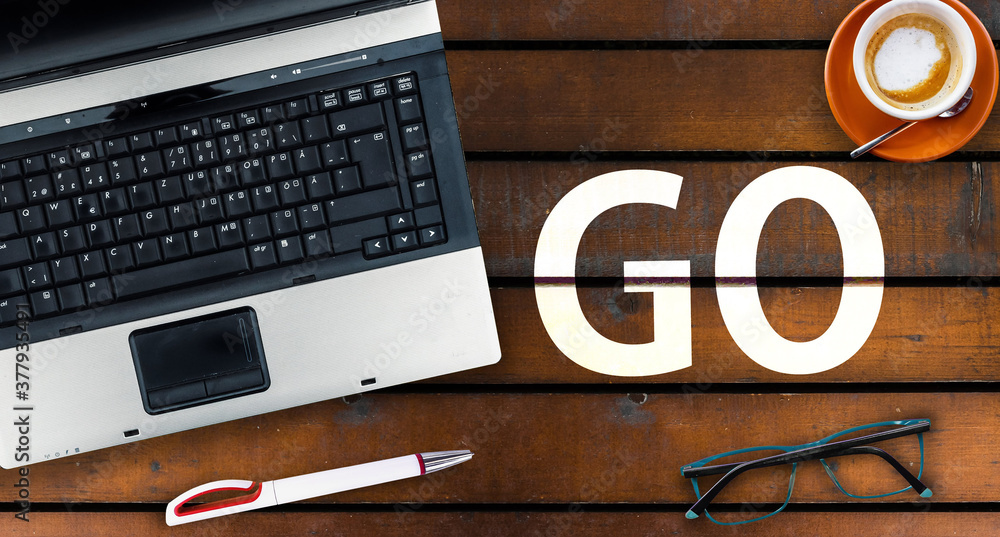 Poster go programming language. word go and laptop, glasses and coffee on wooden table