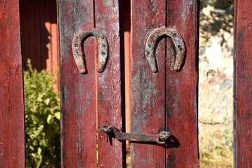 Red wooden door with lock and two nailed lucky horseshoes.
