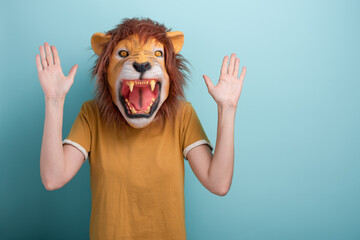 Young woman in lion mask holding hands up in desense or stop gesture.