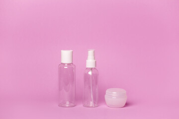 Cosmetic bottles and jars on a pink background