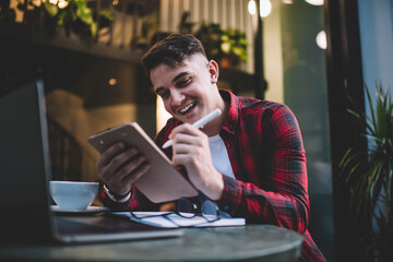 Joyful man writing on clipboard in cafe