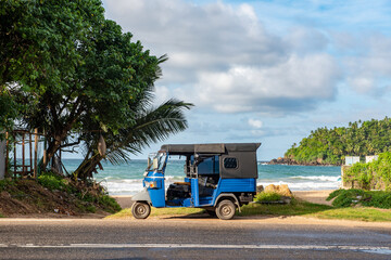 View of the street of Mirissa town with a taxi made of a moped (tuk-tuk) on the background of the...
