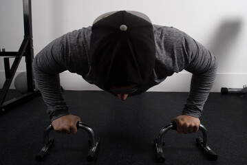 Closeup shot of a young fit male working out on push-up grips