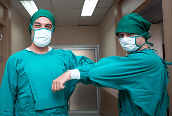 Fototapeta na wymiar Caucasian surgeon doctor elbow bump greeting for social distancing with friend co-worker in hospital hallway. new normal etiquette concept during Coronavirus or Covid-19. Healthcare and medical