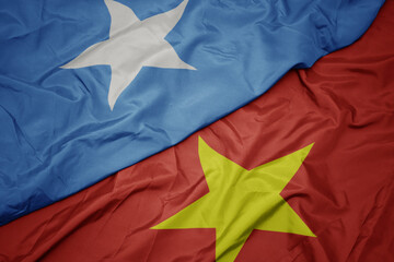 waving colorful flag of vietnam and national flag of somalia.