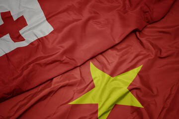 waving colorful flag of vietnam and national flag of Tonga .