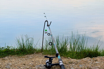 Fishing rod bell on fishing line, lake at sunset background
