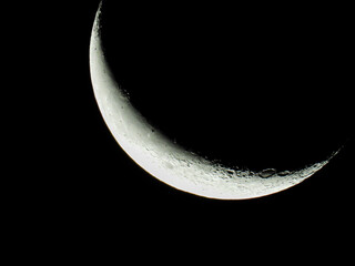 a waning moon stands as crescent moon in the black night sky