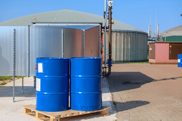 2 big blue barrels stand on a wooden pallet in front of a biogas plant
