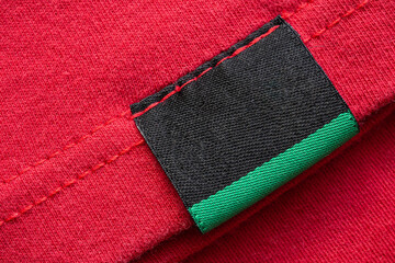 Black blank laundry care clothes label on red cotton shirt background