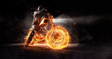Dark motorbiker staying on burning motorcycle at night.
