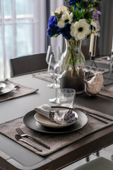 Home Inerior with dining room table setting with black stainless cutlery and ceramic tableware setting on nartual walnut wood top / interior design