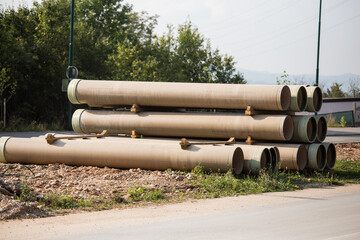 Large sewer pipes, slid along the road, ready for installation, reconstruction of roads and sewer networks