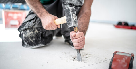 Bauarbeiter schlägt mit Hammer und Meissel ein Loch in den Estrich um die Feuchtigkeit des...