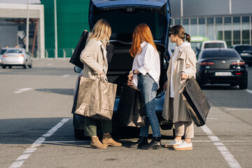 Young women at the car with shopping bags