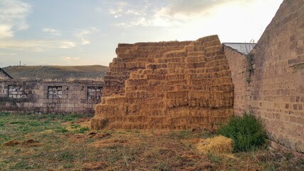 Haystack next to the barn. Stacked straw bales of hay. Square haystack under the open sky. Animal feed. Agricultural background. Concept of the village.