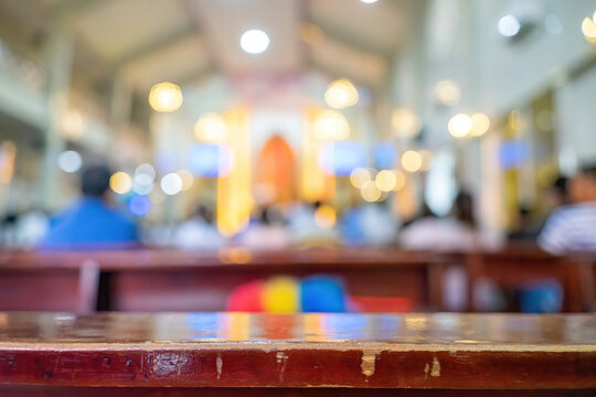 A blurred background photo of the inside of a Vietnamese church sanctuary that is filled with people in the pews, and the pastor stands under a large cross at the altar, in Vietnam.