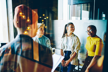 Group of youthful hipsters communicating during friendly meeting for brainstorming collaboration in...