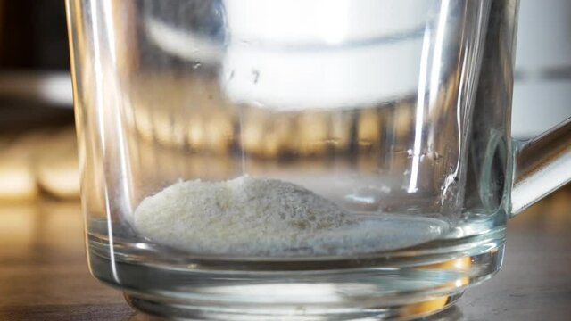 Pouring magnesium vitamin powder into glass cup in close up shot