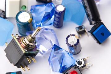 Closeups of capacitors and switches set against a white background with blue marbles and crystals in the foreground.