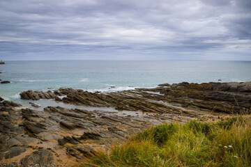 Fototapeta na wymiar Imagen de la playa cielo nublado rocas y hierba en un viaje a cantabria
