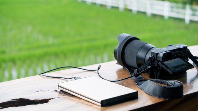 A digital camera charging a power bank that sits on the table and looks out into the field.