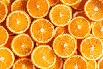 Closeup top view of pattern, laid out slices of juicy oranges on background. Summer tropical citrus fruit for preparing cool freshly squeezed juices, cocktails, drinks, beverages concept.
