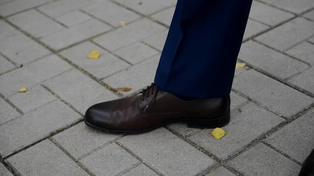 The Guy In The Shoes Stomps His Foot On The Pavement. Foot Close-up