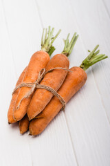 fresh carrots tied with rope on white wooden table