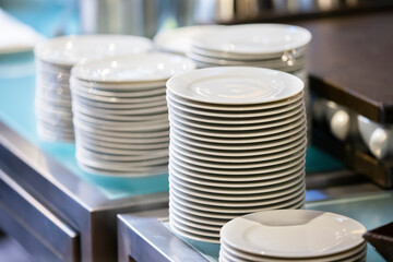 Stacks of empty white plates on a restaurant table.