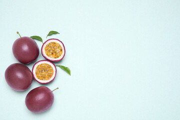 Fresh ripe passion fruits (maracuyas) with leaves on light background, flat lay. Space for text