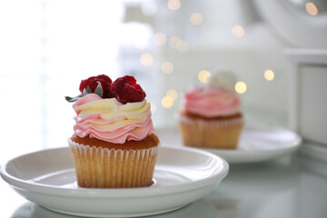 Delicious cupcake with raspberries on table against blurred lights, closeup. Bokeh effect