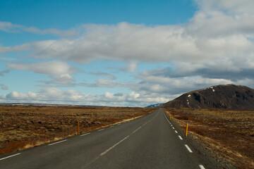 asfaltowa droga na równinie z widokiem na wzgórze 