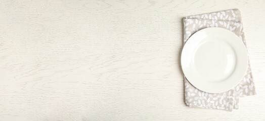 Empty plate and napkin on white wooden table, top view. Space for text