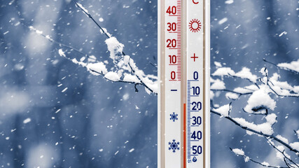 The thermometer on a background of a snow-covered tree branch shows minus 15 degrees