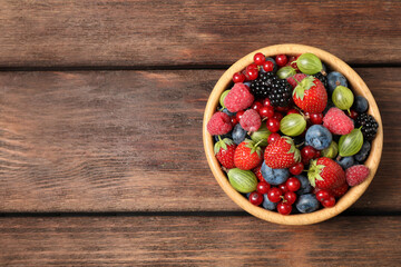 Mix of ripe berries on wooden table, top view. Space for text