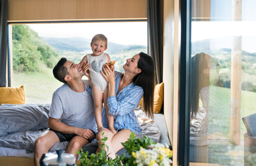 Young woman with husband and baby indoors, weekend away in container house in countryside.