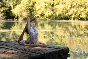 A young beautiful woman practicing yoga in a park in late summer. Health lifestyle concept stock photo.