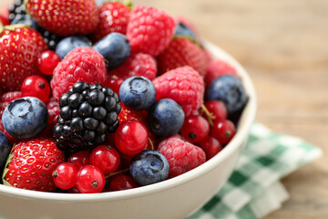 Mix of ripe berries in bowl on table, closeup