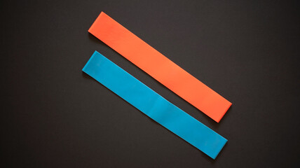 Multi-colored elastic rubber bands for fitness on a white wooden background. A set of rubber bands of different colors - red and blue. Ideal for training at home.