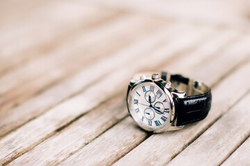 Men's wrist watch with black strap lies on wooden surface. Selective focus.