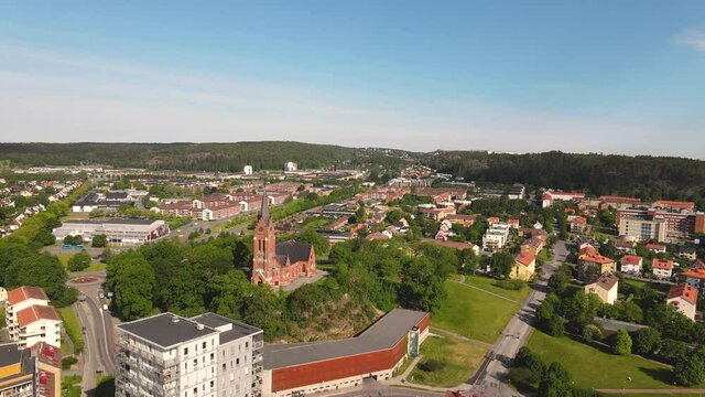 Scenic Distant View Of The Famous Fassberg Church Surrounded By Lush Trees In The Town Of Molndal, Sweden - ascending drone shot