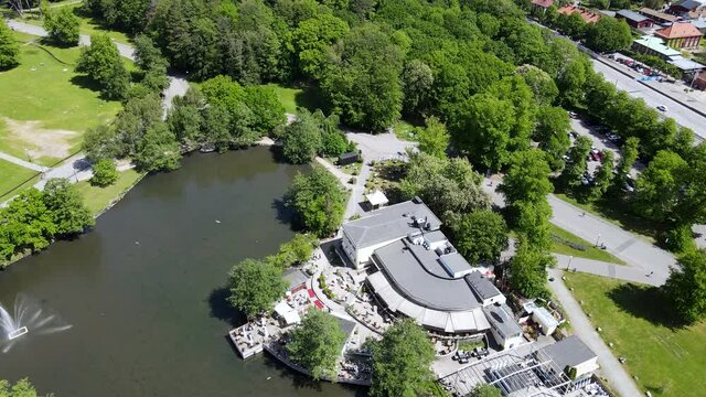 Calm Lake Surrounded By Green Trees Under The Vibrant Sunlight In Slottsskogen Park In Gothenburg, Sweden - aerial drone