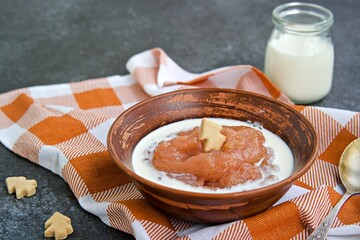 Dessert, thick rhubarb jelly or kissel  in a clay bowl on a dark background. Served with cream.
