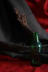 Composition of a bottle with dried flowers on black and red fabric