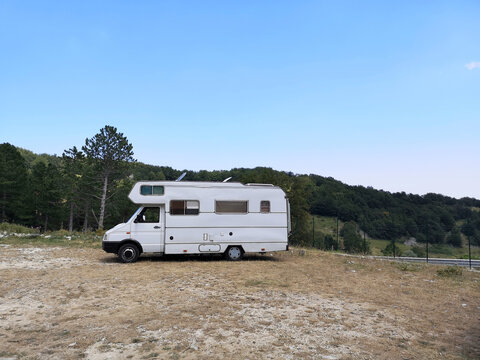 View Of A White Compact Van On A Hill With A Clear Sky Background