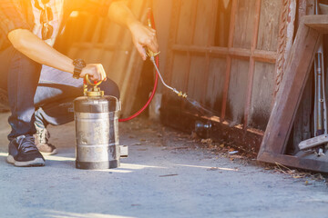 Employees at a termite control company are using a chemical sprayer to get rid of termites at...