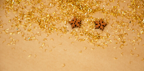Holiday background with golden decoration and wooden snowflakes. Festive background isolated on beige. Christmas and New Year concept.  Greeting card with copy space. Flat lay, top view.