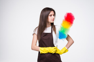 Young woman wearing yellow rubber gloves for hands protection holding colorful duster while cleaning room isolated over white background